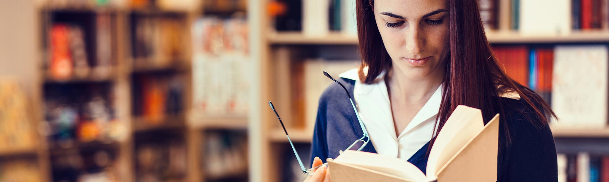 A female reading a booking in a library