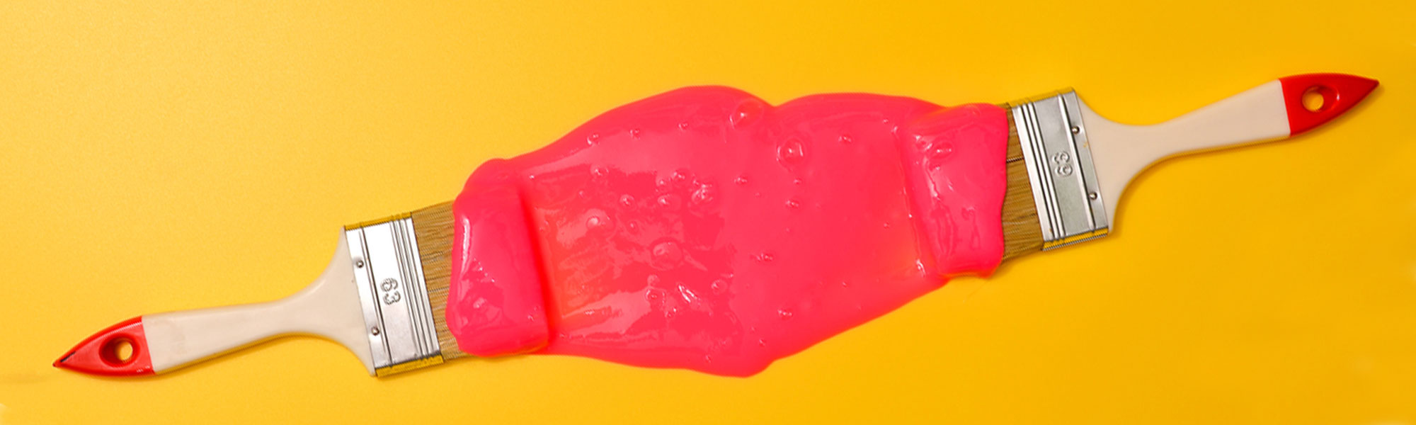 Two paint brushes, red paint on a bright yellow background