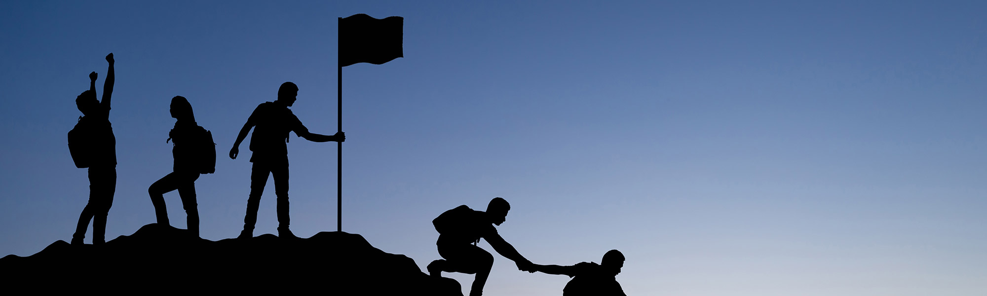 A group of people helping each other climb a mountain