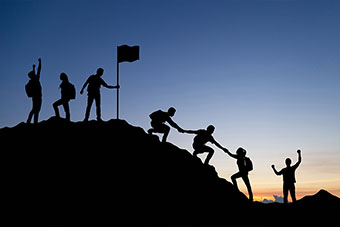 A group of people helping each other climb a mountain